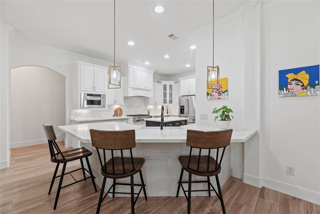 Your chef-inspired kitchen is ready to impress! This beautifully designed space boasts gleaming quartz countertops, a coordinating backsplash, and sleek stainless steel appliances. The crisp white cabinetry, enhanced with updated hardware, is perfectly complemented by under-cabinet lighting and recessed lighting, creating a bright and inviting ambiance. At the heart of it all, a sprawling island with breakfast bar seating offers the perfect spot for casual dining and entertaining.