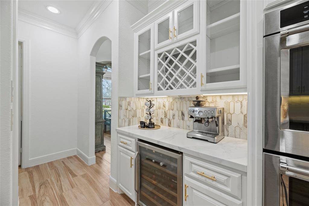 Crisp white cabinets with updated hardware provide a clean and timeless look in the butlers pantry, enhancing the sense of brightness and openness in the space.