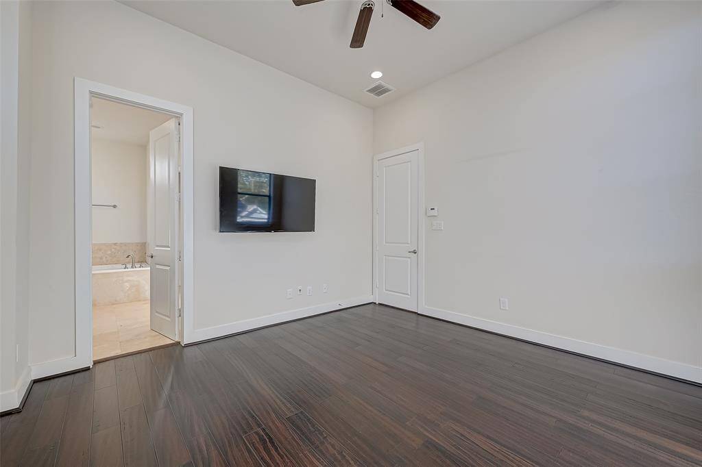 This alternate view of the primary bedroom offers a glimpse into the ensuite bathroom, creating a seamless connection between the two spaces. The layout enhances privacy and convenience while maintaining a clean, modern aesthetic.