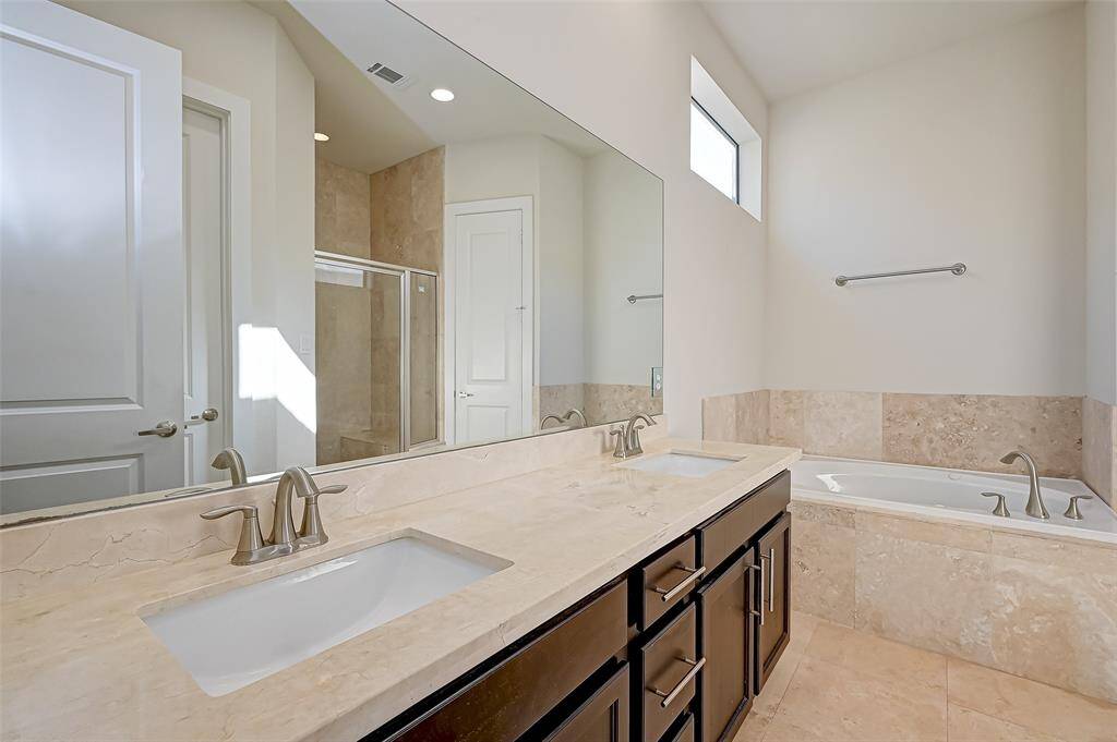 The primary bathroom is a luxurious retreat featuring double sinks with a long mirror, a jetted soaking tub for ultimate relaxation, and a separate walk-in shower. Thoughtfully designed with both comfort and style in mind.