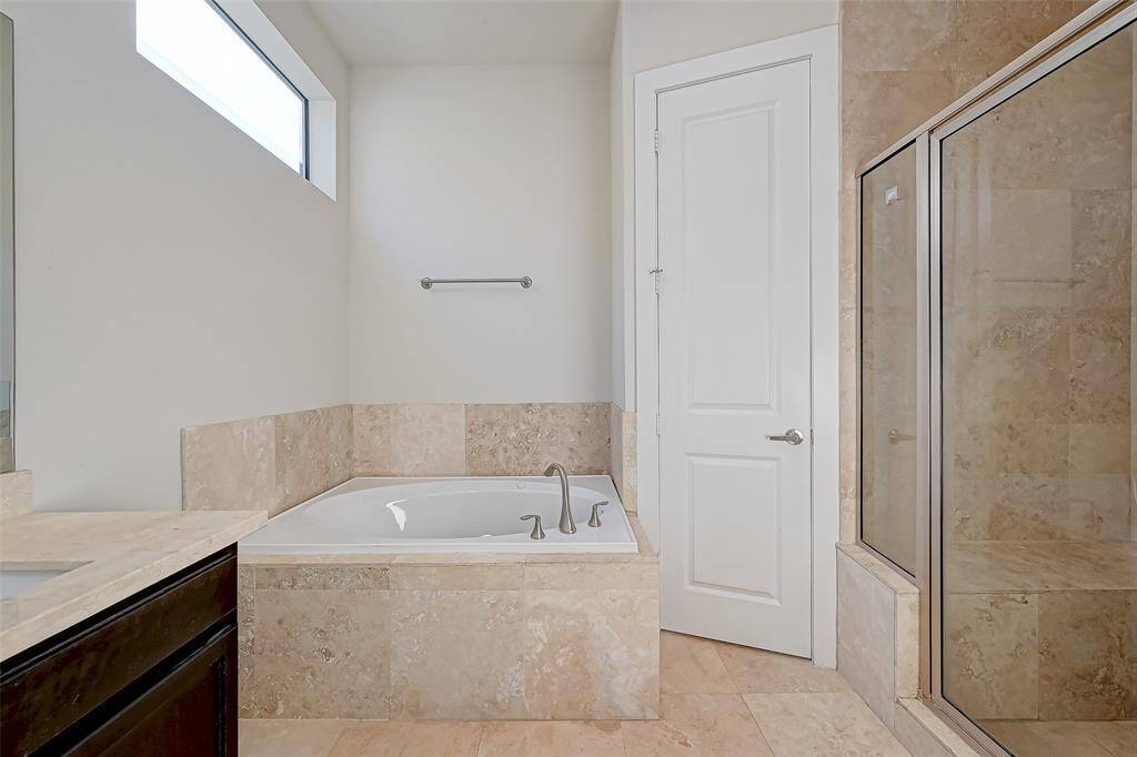 This closer view of the primary bathroom emphasizes the luxurious jetted soaking tub and spacious walk-in shower. Both features offer a spa-like experience, with sleek, modern finishes that elevate the overall design of the space.