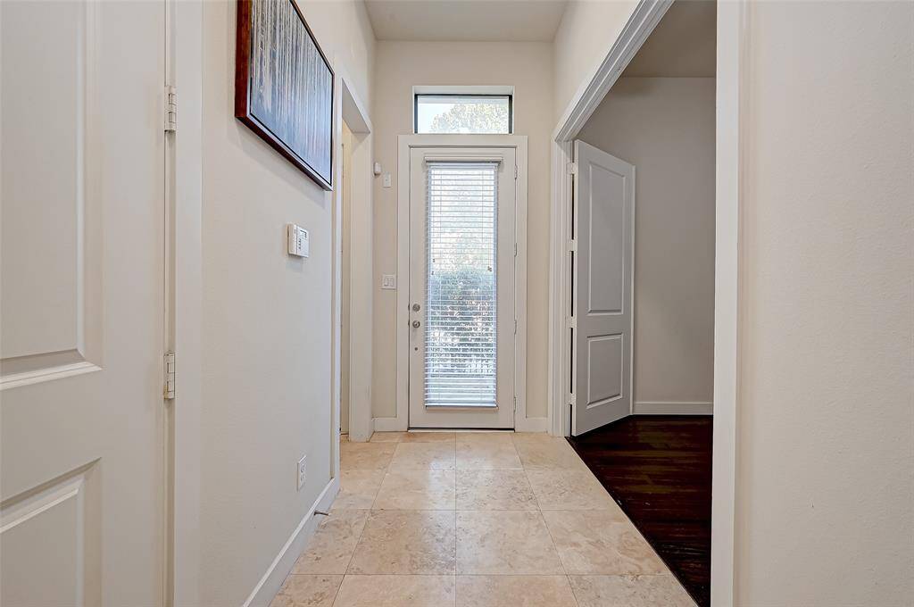 Step inside through the modern glass front door into a bright and inviting entryway. To the right, you'll find a spacious first-floor bedroom, ideal for guests, a home office, or flexible living space. Sleek finishes and thoughtful design welcome you into this contemporary home.