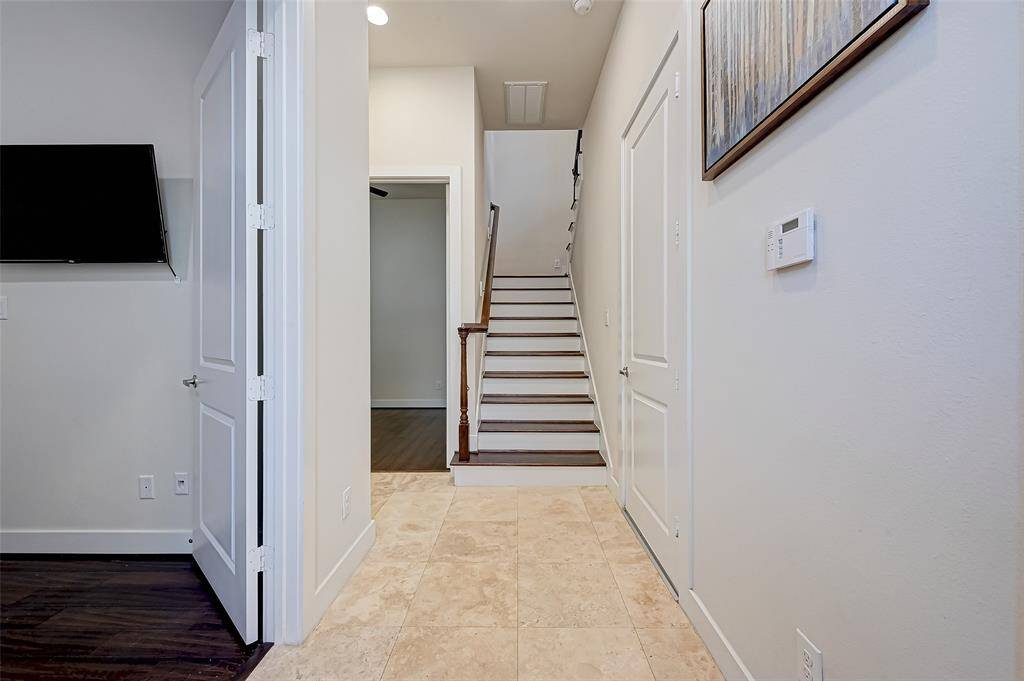 This alternate view of the entryway highlights the home’s functional layout with two first-floor bedrooms, perfect for guests, roommates, or a private home office setup. The open stairway leads you to the second-floor living area, creating a seamless flow throughout the home.