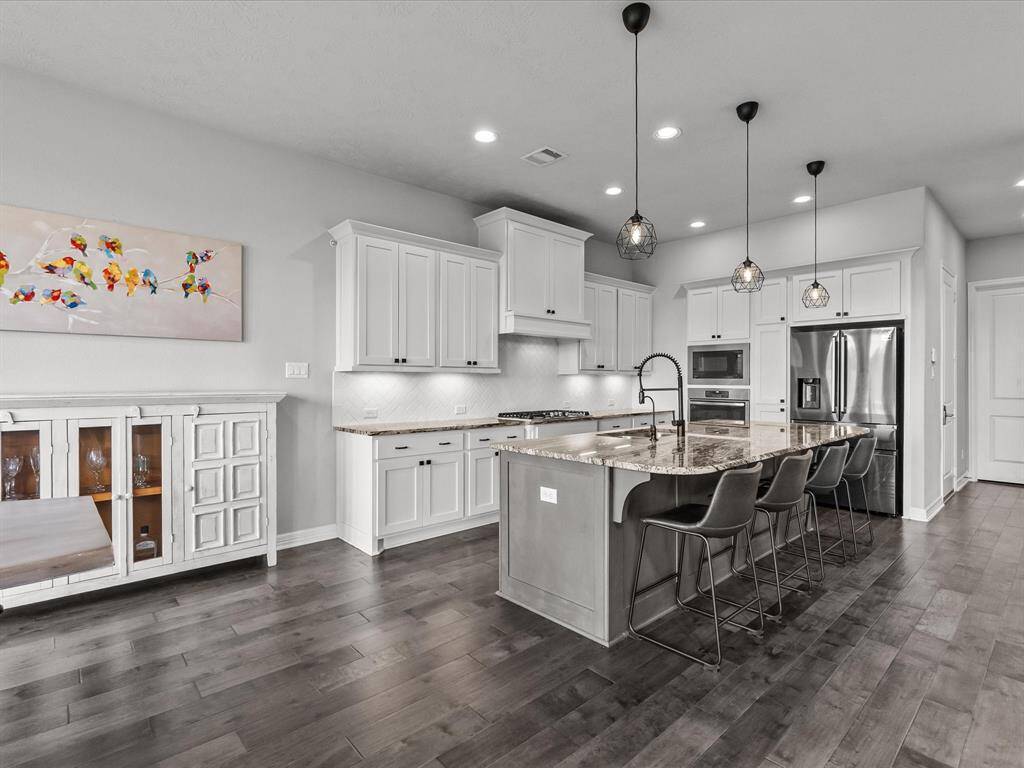 Chef's eat-in island kitchen features 42" cabinets with crown molding, under cabinet lighting, designer backsplash, stainless steel appliances and legthy countertops