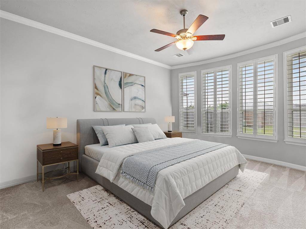 Primary bedroom located on the first floor features plantation shutters, crown molding and a private en-suite bath