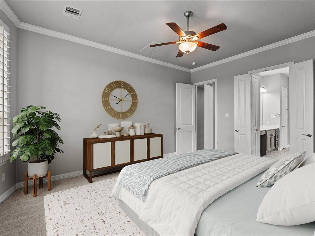 Primary bedroom located on the first floor features plantation shutters, crown molding and a private en-suite bath