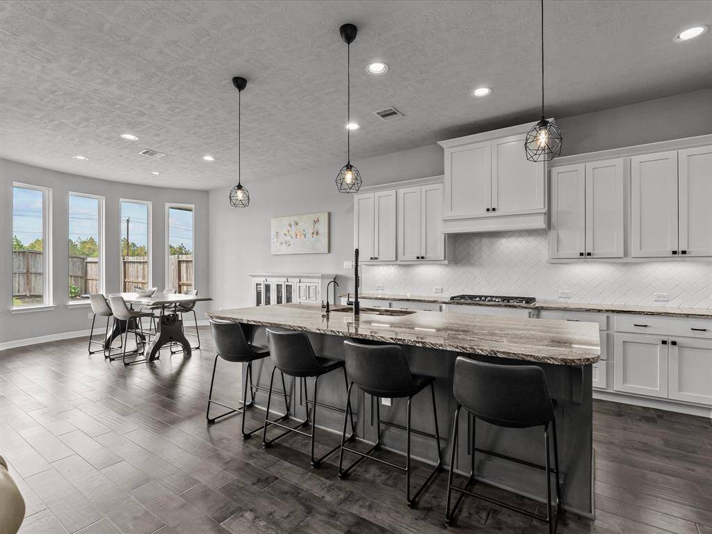 Chef's eat-in island kitchen features 42" cabinets with crown molding, under cabinet lighting, designer backsplash, stainless steel appliances and legthy countertops