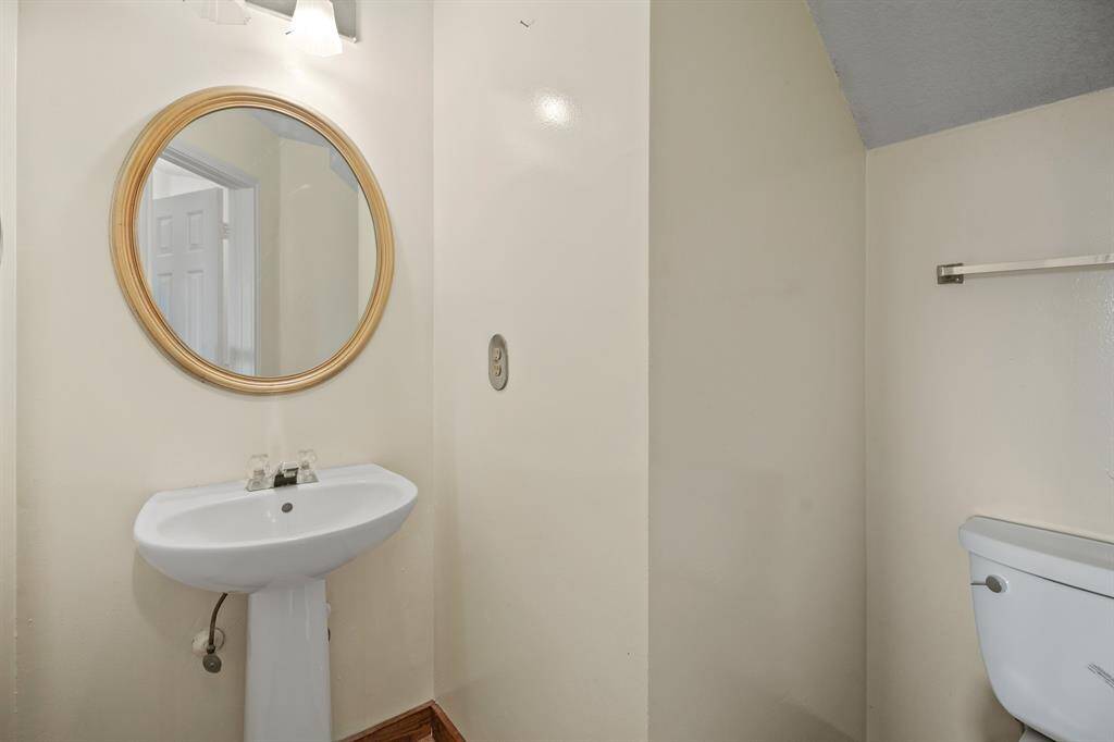 This is powder bathroom featuring a pedestal sink and conveniently located next to the family room.