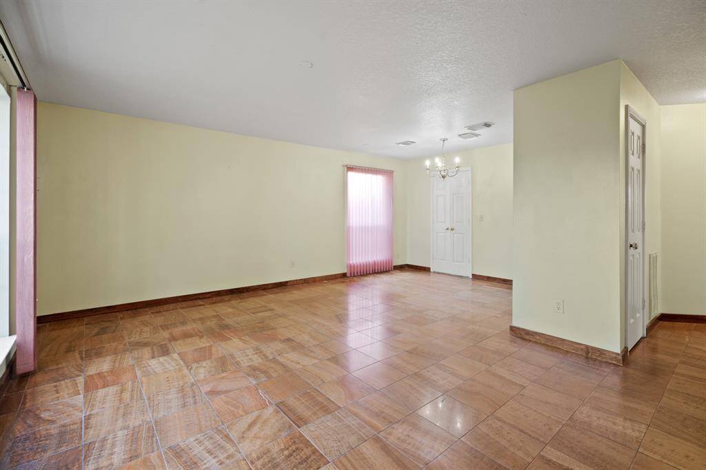 This spacious family room features a neutral palette, tiled flooring, and large windows. It is ideal for a living or dining area combo and offers ample natural light and a clean, open layout.