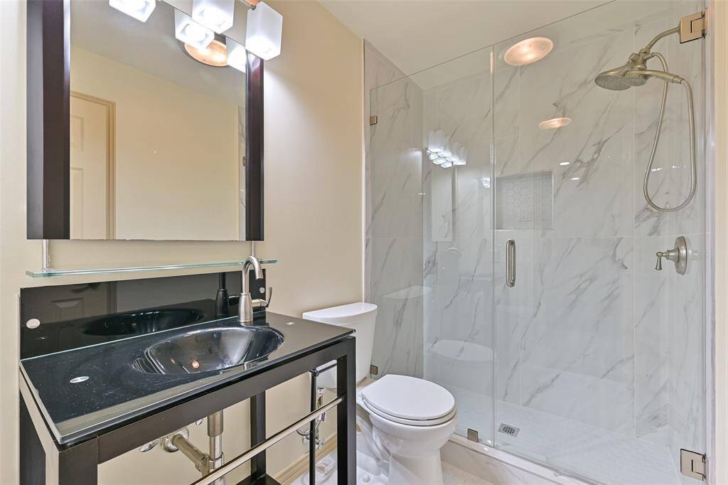 Elegant black vanity and detailed tile work elevate the design of the ensuite bathroom.