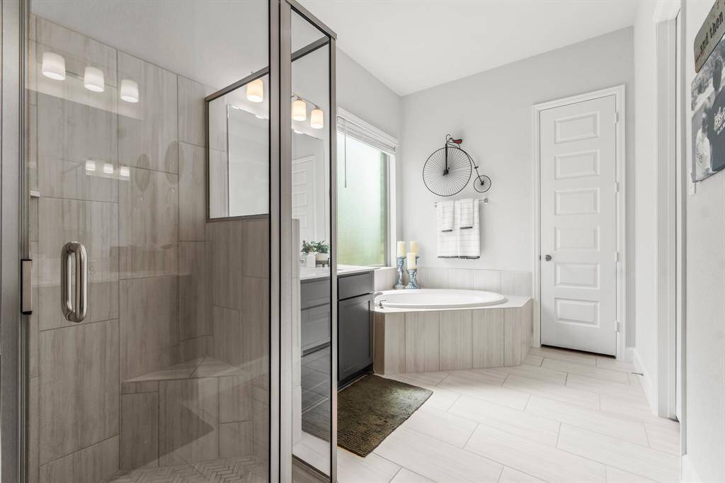 Primary bathroom showcases large tile, separate vanities for personal space and storage. A spacious walk-in shower is complemented by a large soaking tub. The thoughtful layout balances functionality with a spa-like feel.
