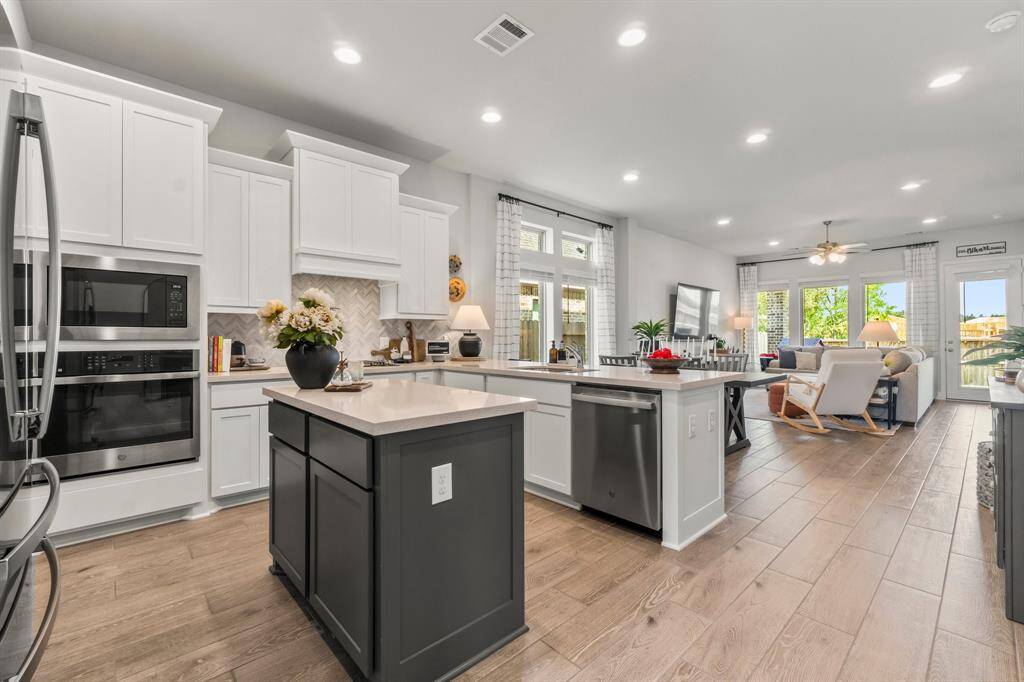 Kitchen features white cabinet, clean look, with stainless steel appliances. At the center, a kitchen island without a cooktop serves as a functional focal point offering, ample prep space and extra storage.