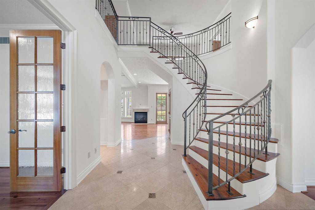 Elegant entry with curved staircase and travertine floors.