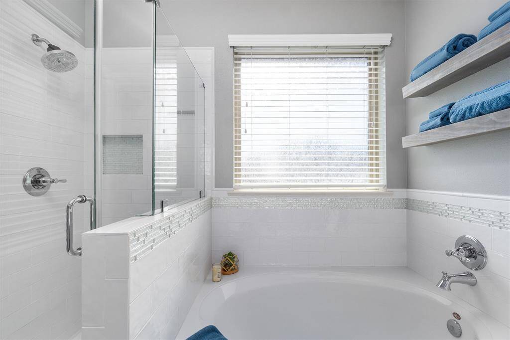 Relaxing garden tub and stand alone, fully tiled shower with seamless glass