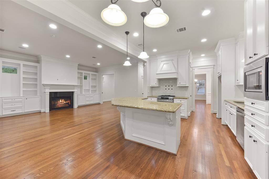 The living room, featuring hardwood floors, built-in shelving, and a cozy fireplace, opens seamlessly to the kitchen, creating the perfect space for easy entertaining.