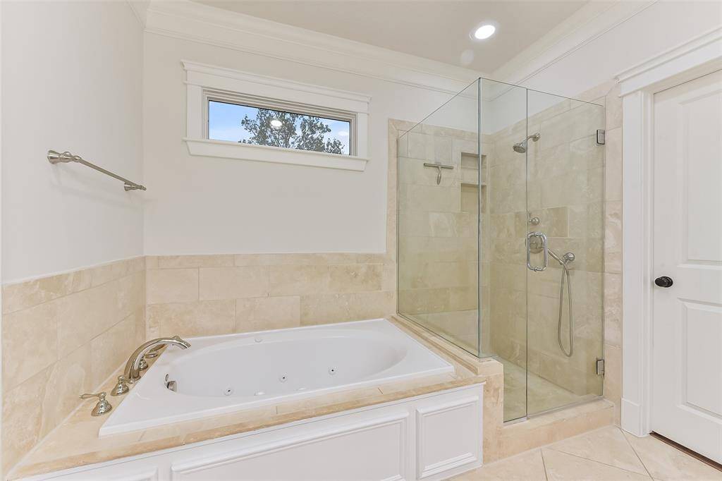 Another view of the primary bathroom’s jetted bathtub and glass shower.