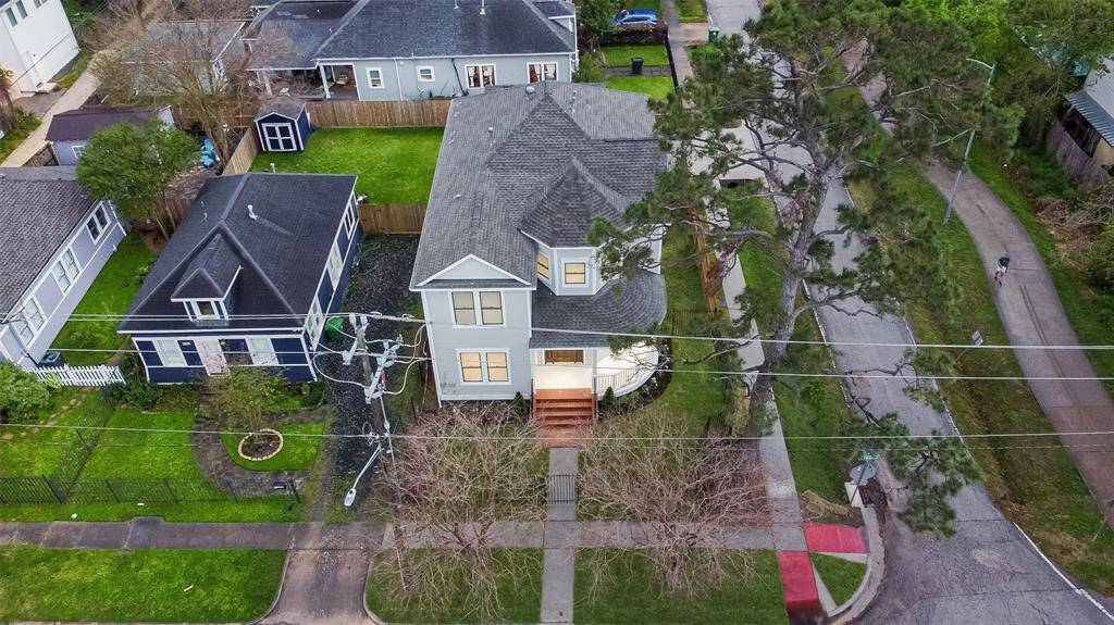 This aerial view showcases the charming two-story home with a spacious front yard and mature trees. The property is situated on a corner lot in a quiet neighborhood, right across from the hike and bike trail.