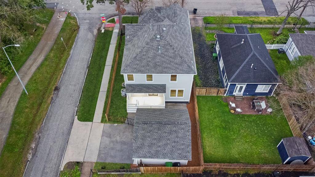 Another aerial view showcases the two-story home with a detached garage and a spacious backyard. The property is bordered by a wooden fence and is located on a corner lot, across from the hike and bike trail.