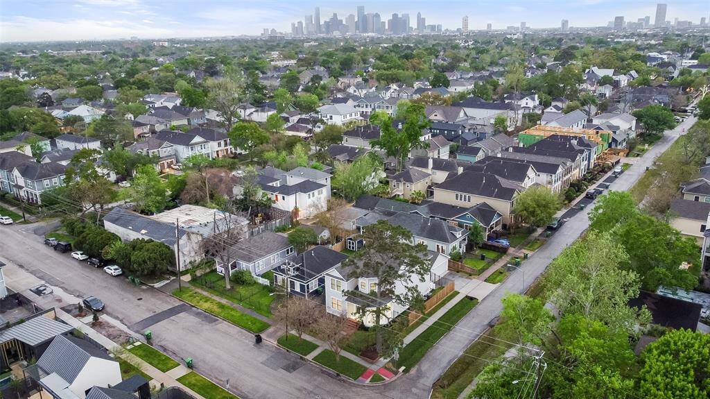 The home is situated in the Houston Heights, a peaceful and residential neighborhood close to urban amenities. The Houston skyline is visible in the distance.