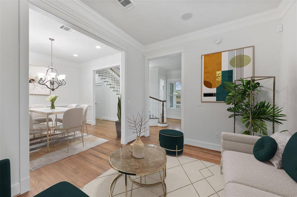 Bright, open formal living room with hardwood floors is open to the formal dining room with elegant wainscoting. This area transitions to a staircase with decorative railing, enhancing the home's charm, sophistication and the welcoming feel. Virtually staged