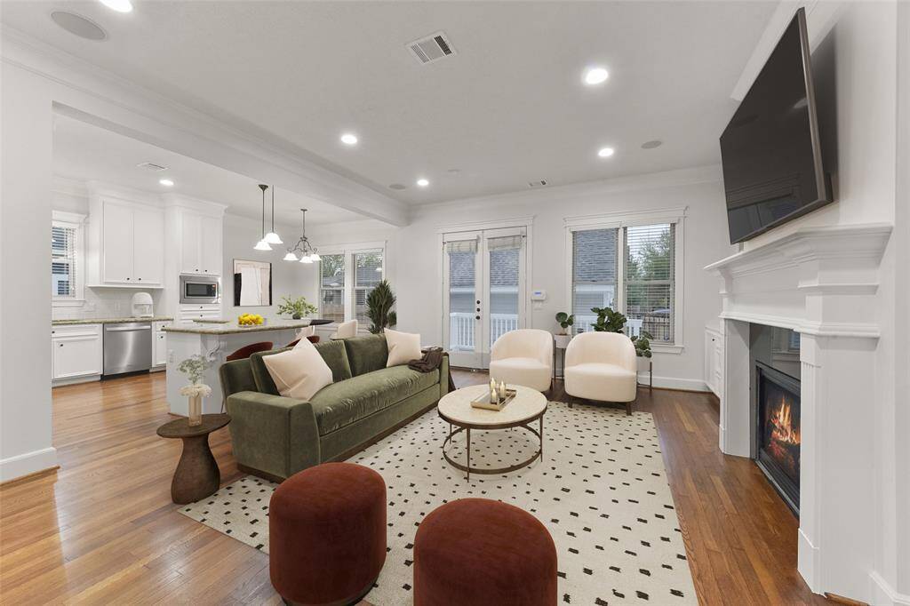 Spacious, open-concept family room features elegant hardwood floors and opens to the modern kitchen with stainless steel appliances. A cozy fireplace with custom built-ins, large windows and French doors opening to the back porch offers plenty of natural light and access to the outdoors. Perfect for entertaining and family living. Virtually staged.