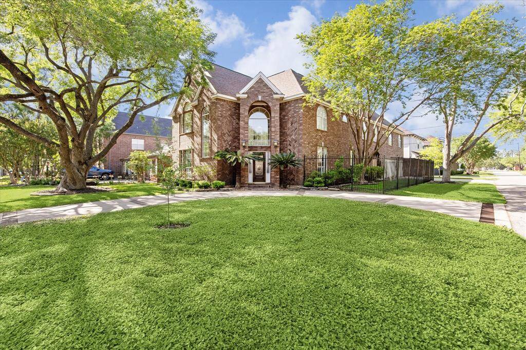 4900 Cedar Street in Bellaire is a stately brick home with classic architectural lines, soaring arched windows, and a grand entry framed by mature trees. Situated on a spacious corner lot, the property features a circular driveway, manicured landscaping, and a gated side yard for added privacy.