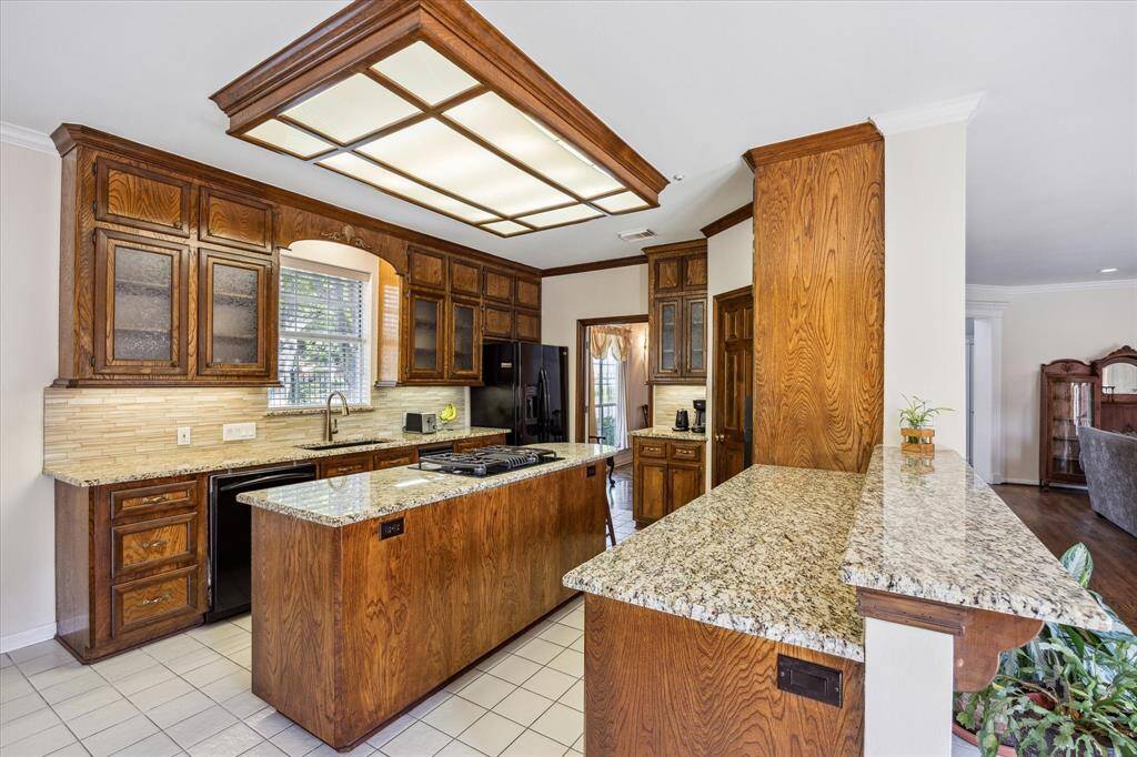This kitchen features granite countertops, a central island with cooktop, and abundant cabinet storage throughout.