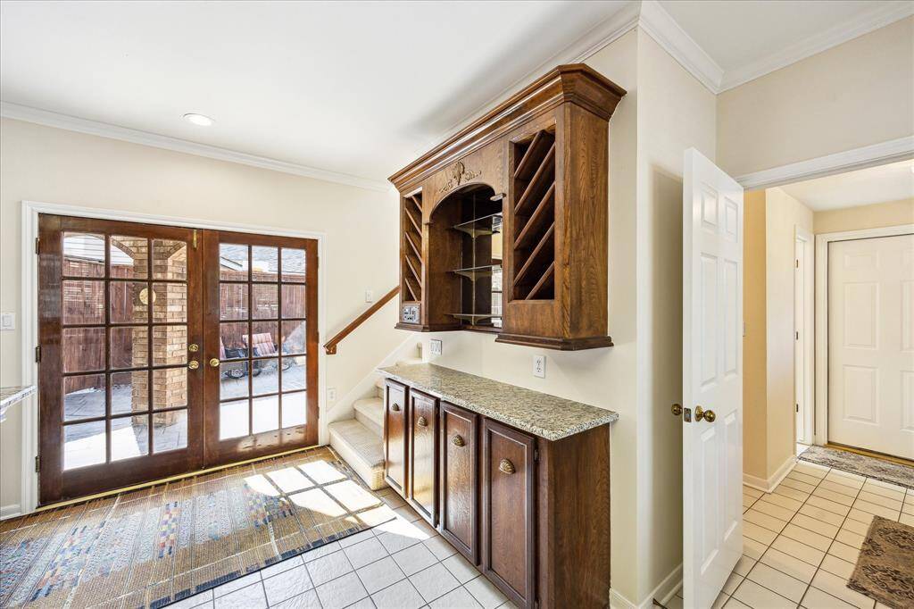 This butler’s pantry includes granite countertops, upper wine storage, and direct access to the patio through French doors.