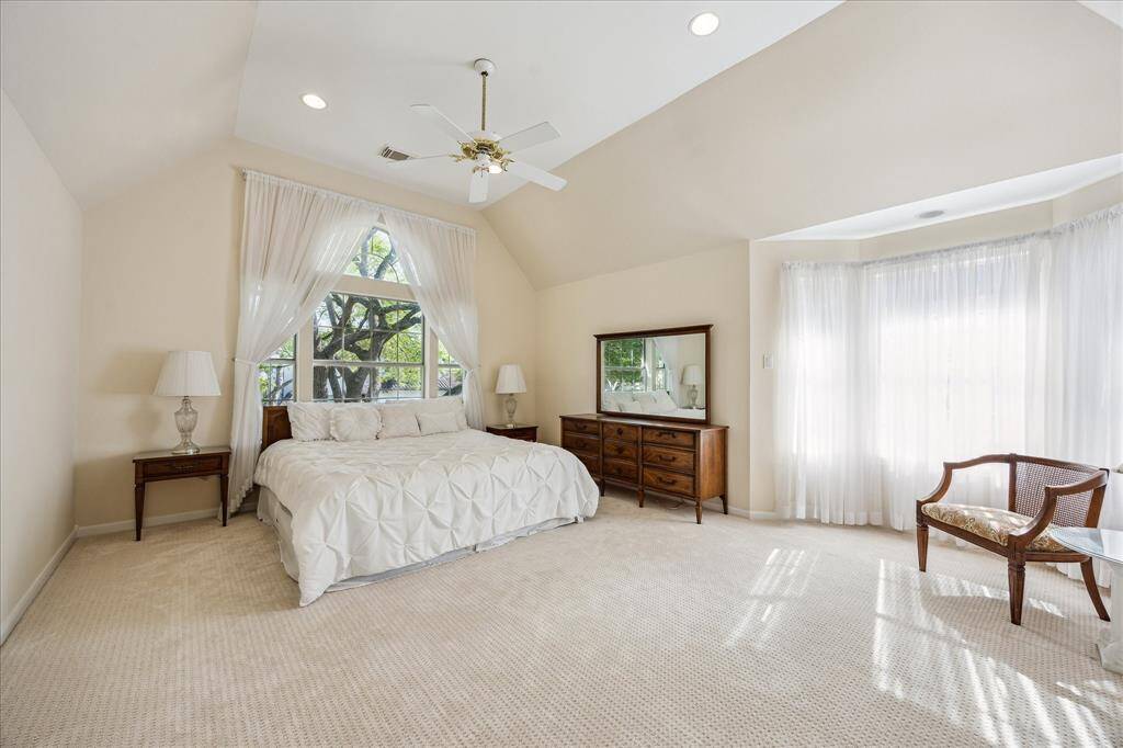 This primary bathroom features a large soaking tub, separate shower, dual vanities, and ample natural light from a wide window.