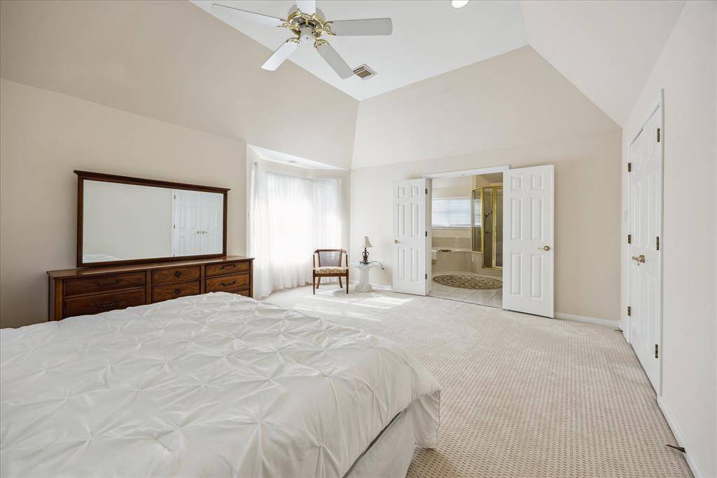This primary bathroom features a large soaking tub, separate shower, dual vanities, and ample natural light from a wide window.