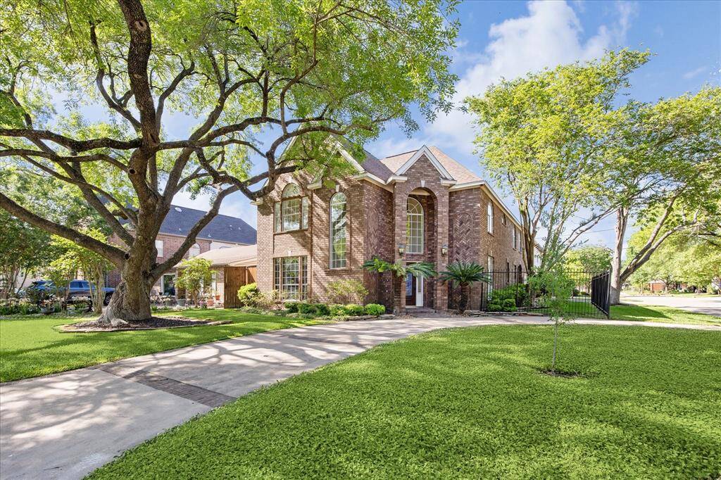4900 Cedar Street in Bellaire is a stately brick home with classic architectural lines, soaring arched windows, and a grand entry framed by mature trees. Situated on a spacious corner lot, the property features a circular driveway, manicured landscaping, and a gated side yard for added privacy.