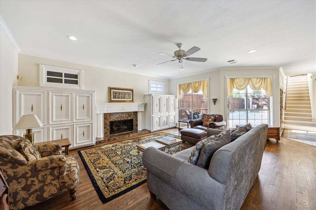 This spacious family room offers a cozy fireplace, rich wood flooring, and large windows that overlook the backyard and pool area.
