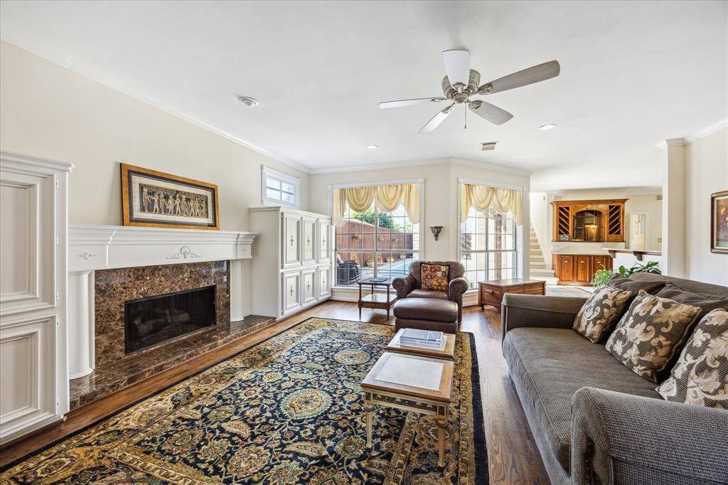This bright family room features hardwood floors, a marble fireplace, and expansive windows overlooking the backyard and pool.
