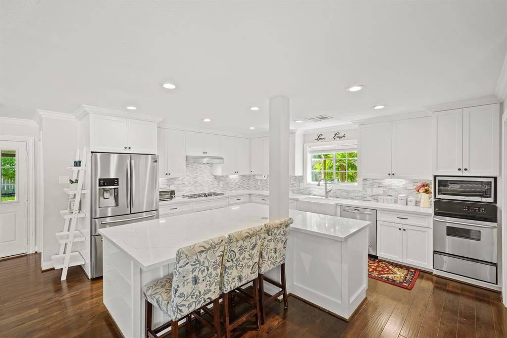 This Amazing Professionally Designed Kitchen touts an L Shaped Quartz Topped (White with Grey Vein) Island/Breakfast Bar (Approximately 7'10" x 6'10") with White Painted Cabinets and Soft Close Drawers.  The Kitchen also features Walnut Hued Handscraped Hardwood Floors and Extended Baseboards.