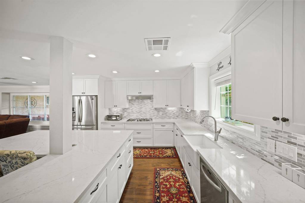 Additional Amenities in the Modern Kitchen include a  White Porcelain Farmhouse Kitchen Sink, Polished Nickel Goose Neck Faucet with Pull Out Spray, Under Cabinet Lighting, Updated Window, and Faux Wood Blinds.
