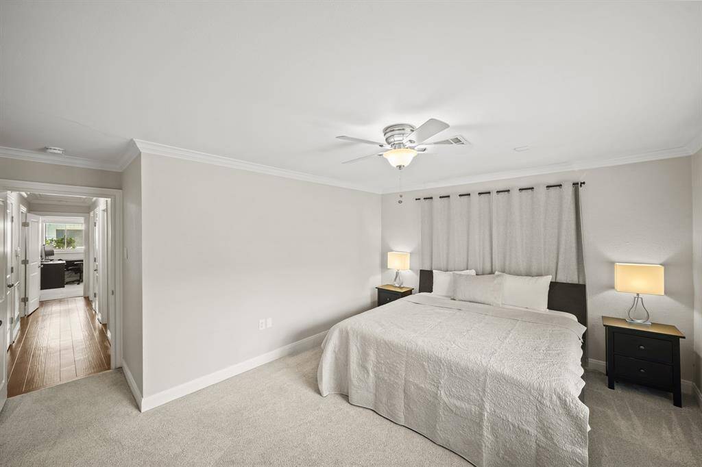 The Primary Bedroom features Light Grey Pile Carpet, Crown Molding, Updated Polished Nickel Ceiling Fan with White Blades, Light Grey Designer Paint with White Trim, and Extended Baseboards.