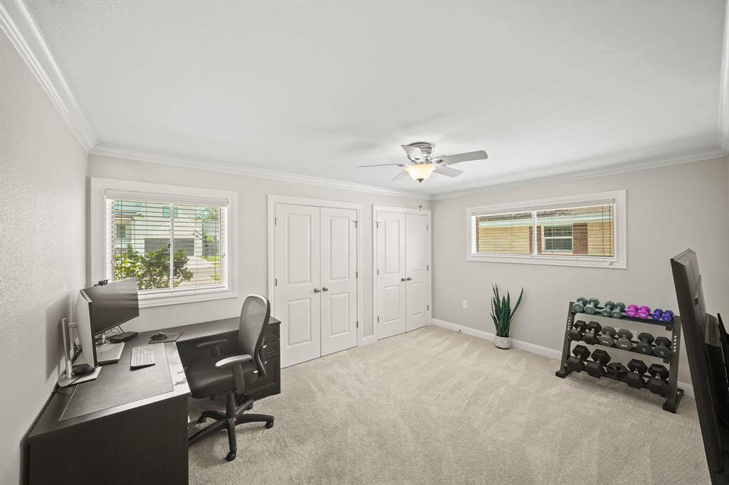 The Second Bedroom features Light Grey Hued Pile Carpet, Crown Molding, Updated Polished Nickel Ceiling Fan with White Blades, Faux Wood Blinds, Light Grey Designer Paint with White Trim, and 2 Closets wtih 2 Panel Double Door Enclosure---One Closet features a Hanging Rod and Built in Shelf; the Other Closet features Built in Shelves.