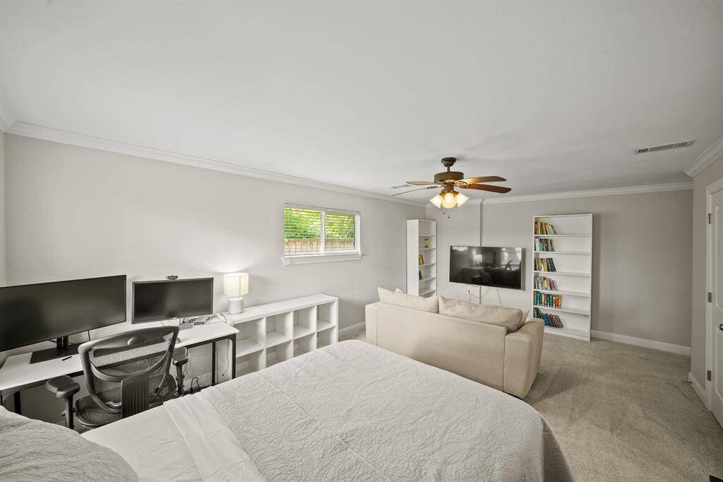 The Fourth Bedroom/2nd Primary Suite/Gameroom/Flex Room features Light Grey Hued Pile Carpet, Crown Molding, and Updated Ceiling Fan with Wood Blades and Opaque Glass Shade.  This Versatile Room adjoins an EnSuite Bath.