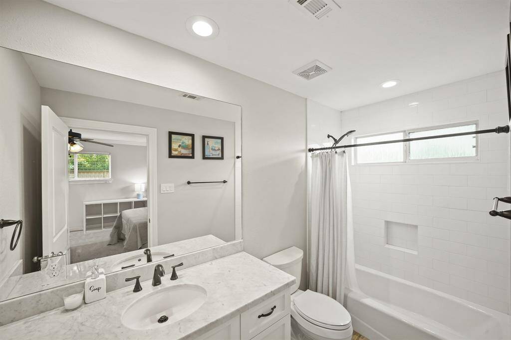 This Well-Appointed EnSuite Bath to the 2nd Primary Suite features a Marble Topped Vanity (White with Grey Vein), Wall Mounted Mirror, and a Kohler Full Tub/Shower wtih White Subway Tile Surround, Built in Shampoo Shelf, Recessed Light, Oil Rubbed Bronze Plumbing Fixtures, and Slider Window.