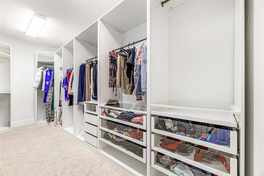 Primary closet with built-in shelves and soft closed drawers.