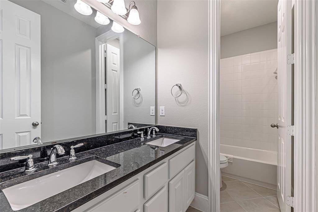 Secondary bathroom with double sinks and tub.