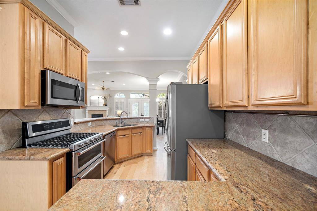 This granite-clad kitchen offers abundant prep space, a five-burner gas range, and a smart open flow into the living and dining areas—ideal for everyday ease and entertaining alike.