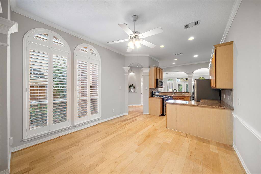 The breakfast area features three tall arched windows with plantation shutters, filling the space with soft light and offering a cozy setting just off the kitchen.