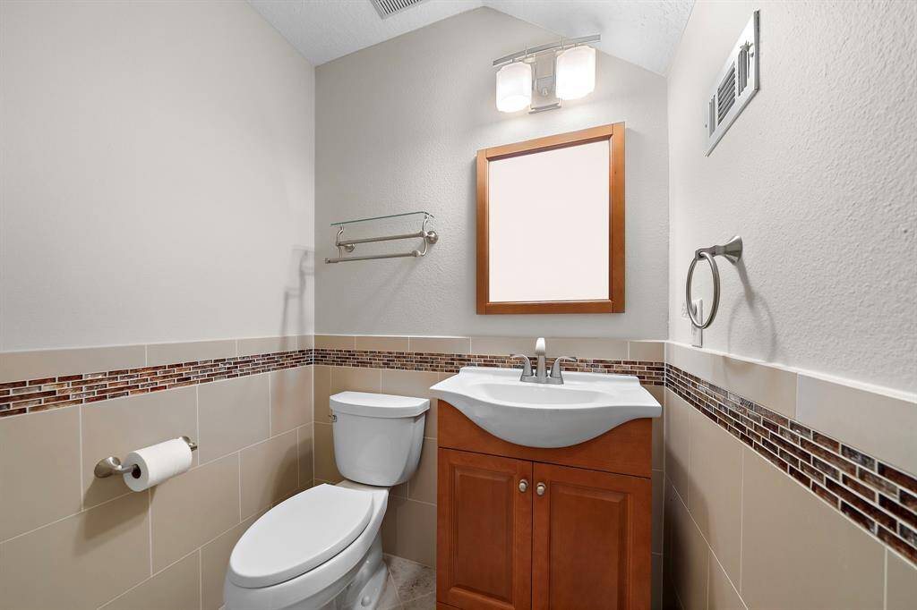 This main-level powder room is smartly styled with modern tile accents, a rich wood vanity, and sleek brushed hardware—perfect for guests and everyday use.