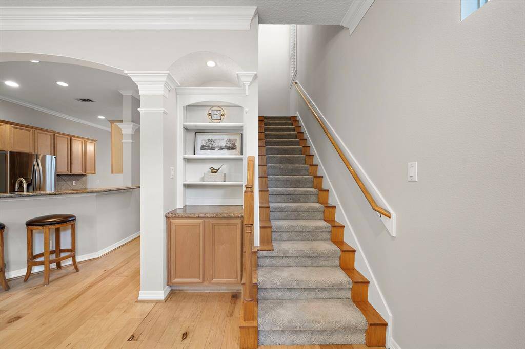 A functional transition to the second floor, this stairwell features soft carpeting, built-in shelving, and clean sightlines into the open-concept living area below.
