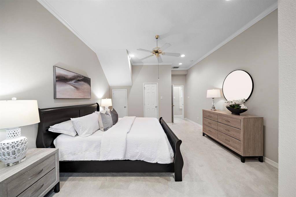The expansive primary bedroom offers serene comfort with neutral tones, plush carpeting, and dual walk-in closets for ample storage.