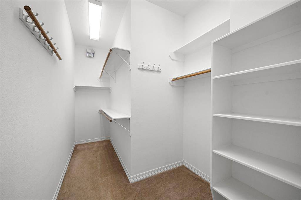 Spacious walk-in closet offers abundant built-in shelving, dual hanging storage, and convenient wall hooks for organizing accessories and garments. Thoughtfully designed to maximize every inch, this closet provides plenty of room for seasonal wardrobes and extra storage needs.