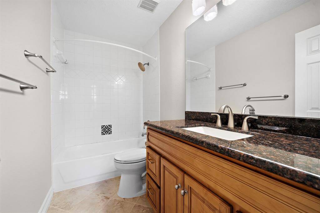 This upstairs bath is equipped with a granite-topped vanity, brushed fixtures, and a sleek tub-shower combo, offering style and function for everyday use.