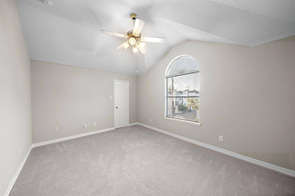Vaulted ceilings and an arched window give this upper-level bedroom architectural interest and views toward the quiet street below.