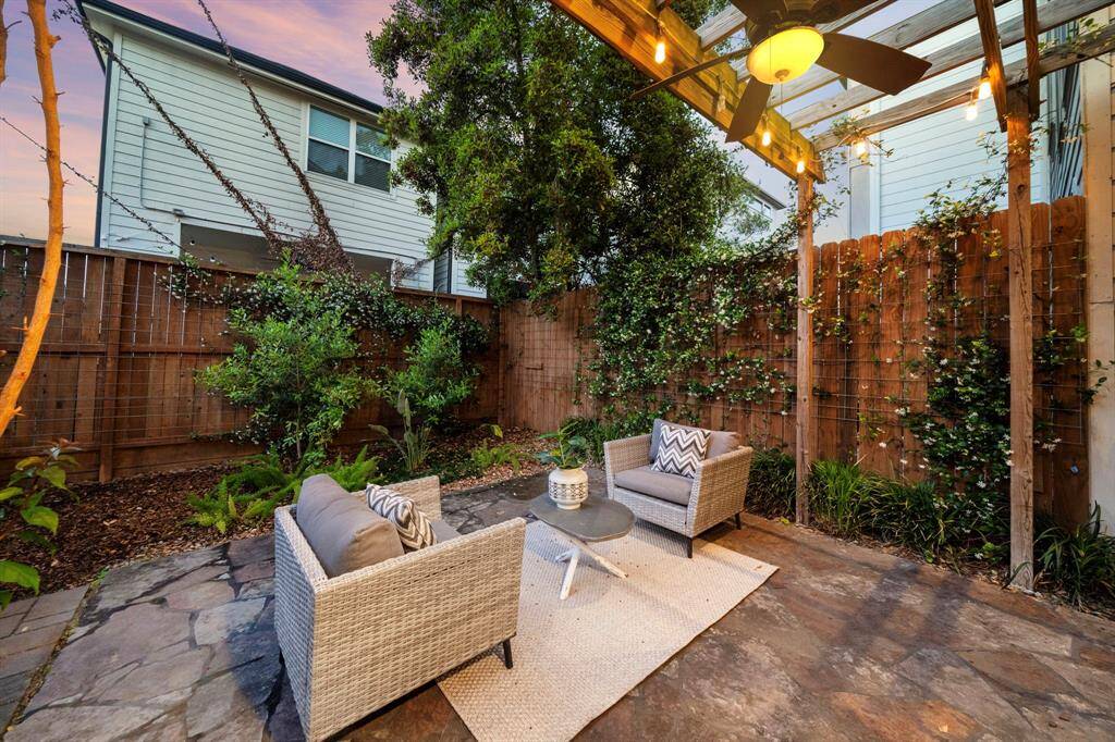 Surrounded by mature greenery and a cedar fence, this private backyard patio is a perfect blend of nature and comfort beneath the soft glow of string lights.